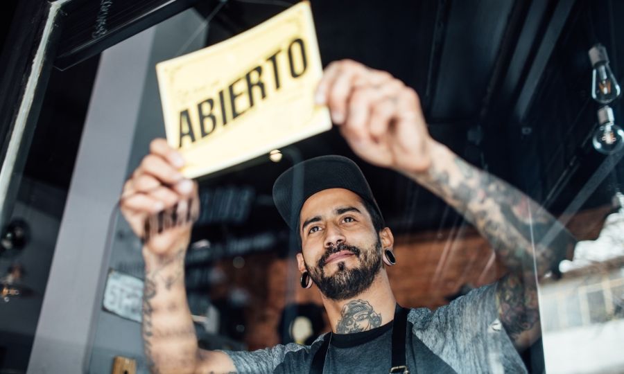 Small business owner flipping "Open" sign in Spanish.
