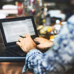 Man at a restaurant writing a document on his laptop.