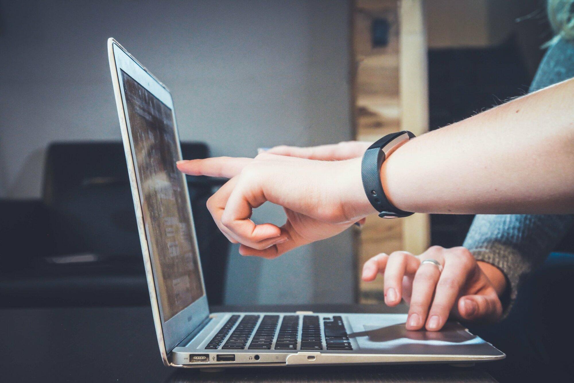 Hands pointing at a laptop screen, highlighting IT services for business.