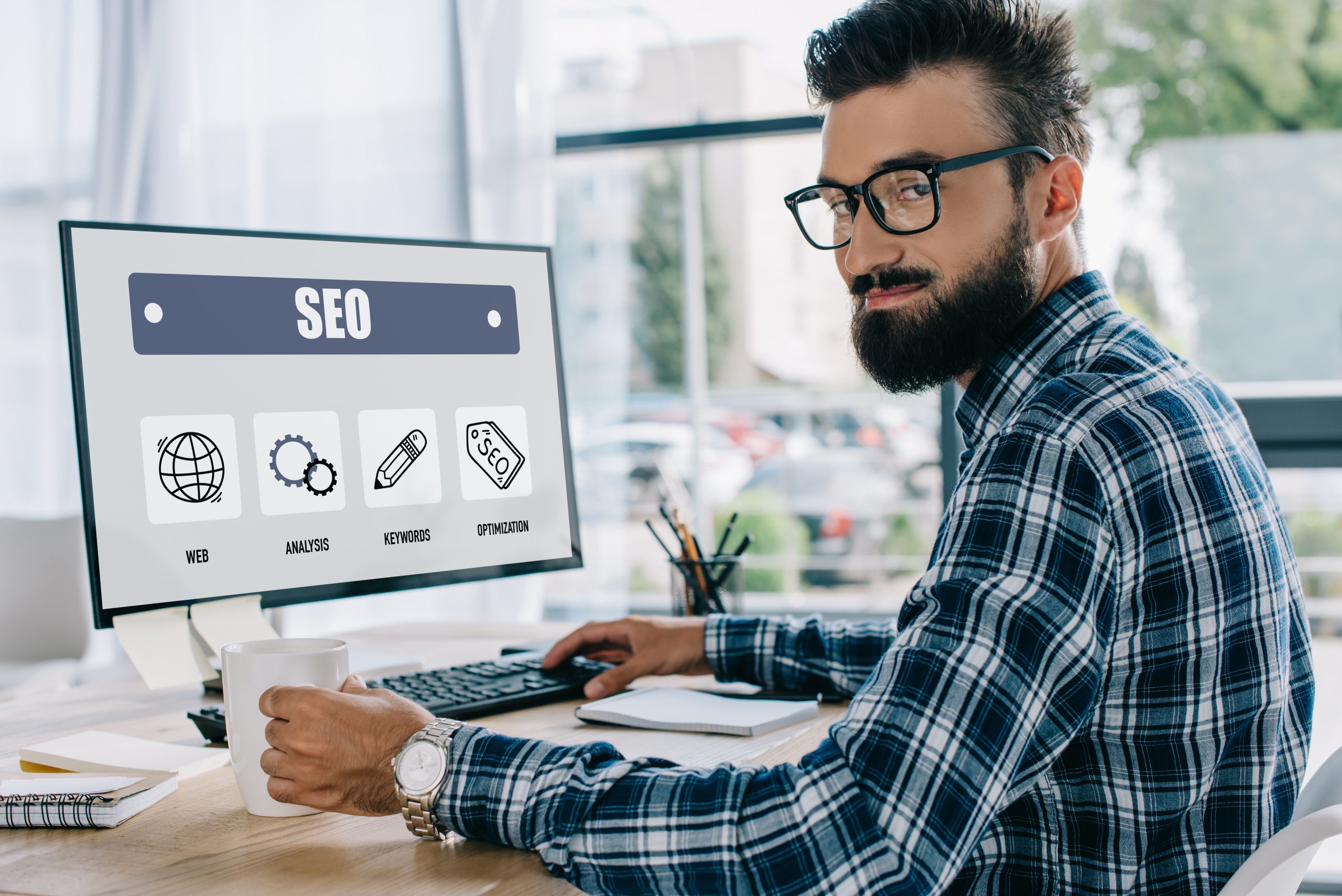 Young SEO manager working at a desk with SEO tools on the computer screen.