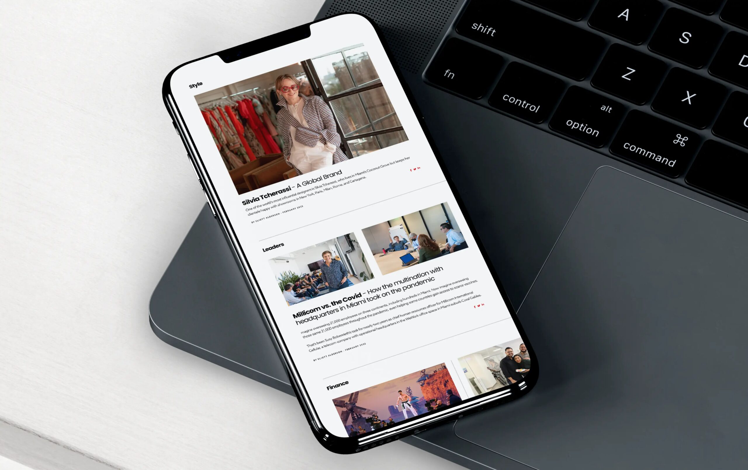 Smartphone displaying a webpage layout, resting on a laptop.