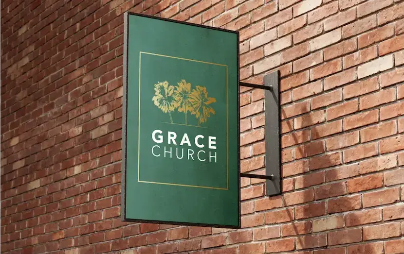 A green signage with gold tree emblem for Grace Church mounted on a brick wall.