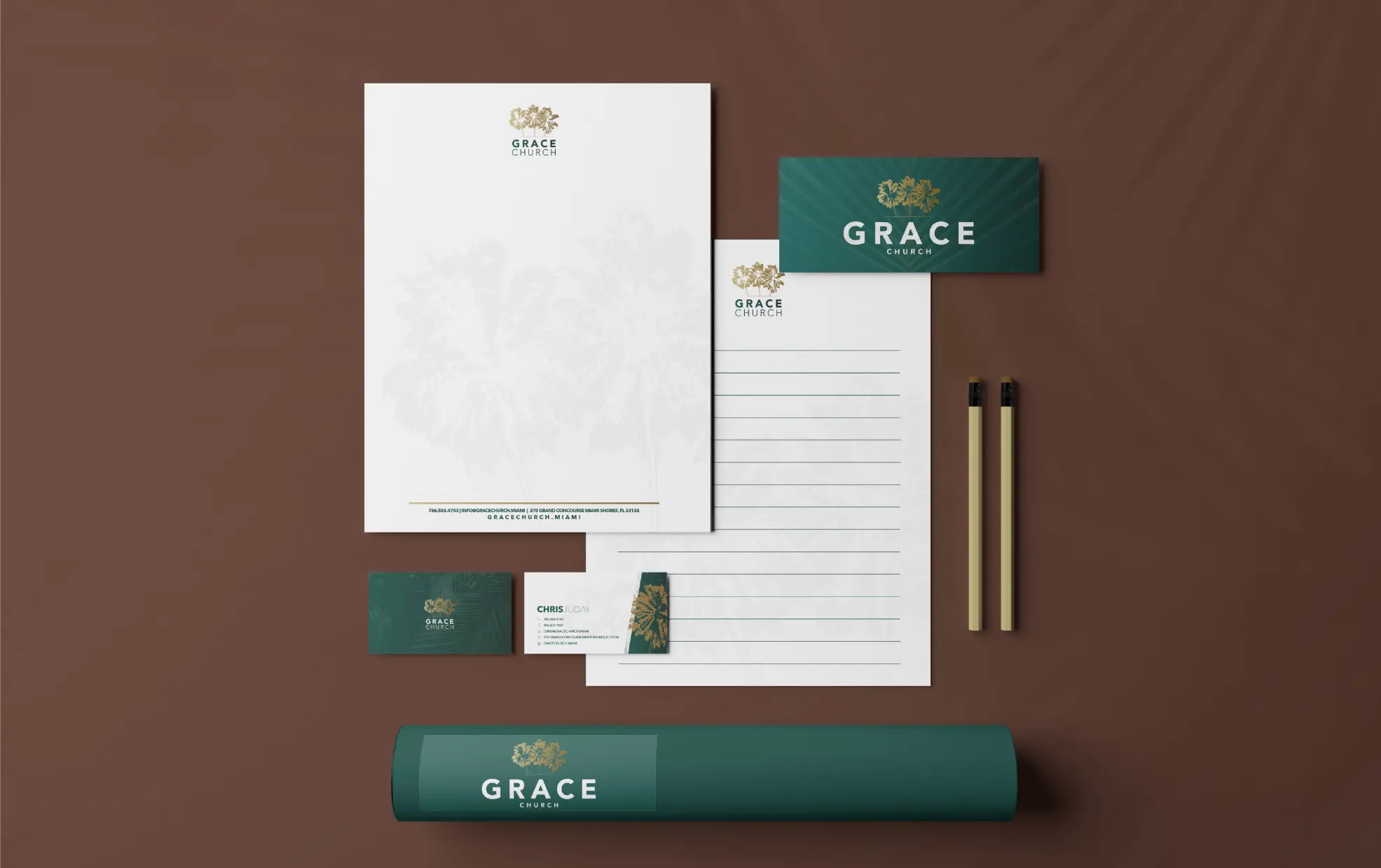 Elegant stationery set with business cards, letterhead, and pens on a brown surface.