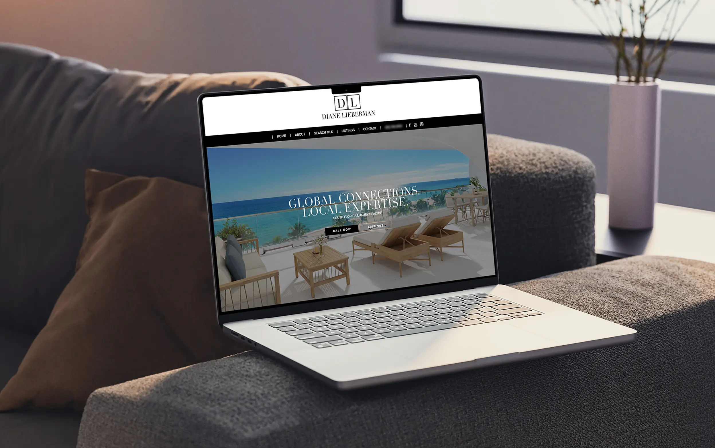 Laptop displaying a website with a beach-themed homepage, placed on a cozy sofa.