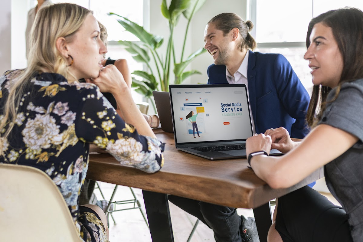 Two marketing professionals discussing social media strategies in a modern office, with laptops and data insights on screen.