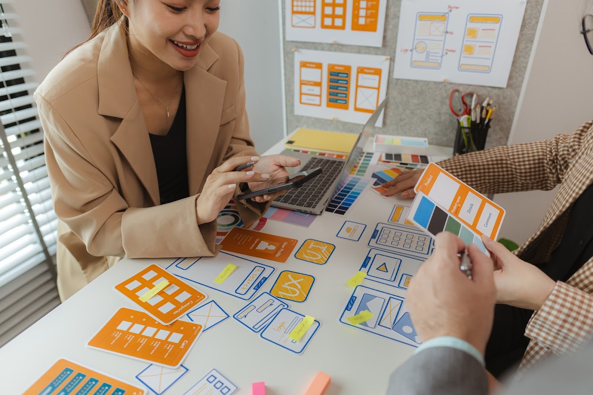 Designers collaborate on creative website layouts with colorful prototypes and digital tools.