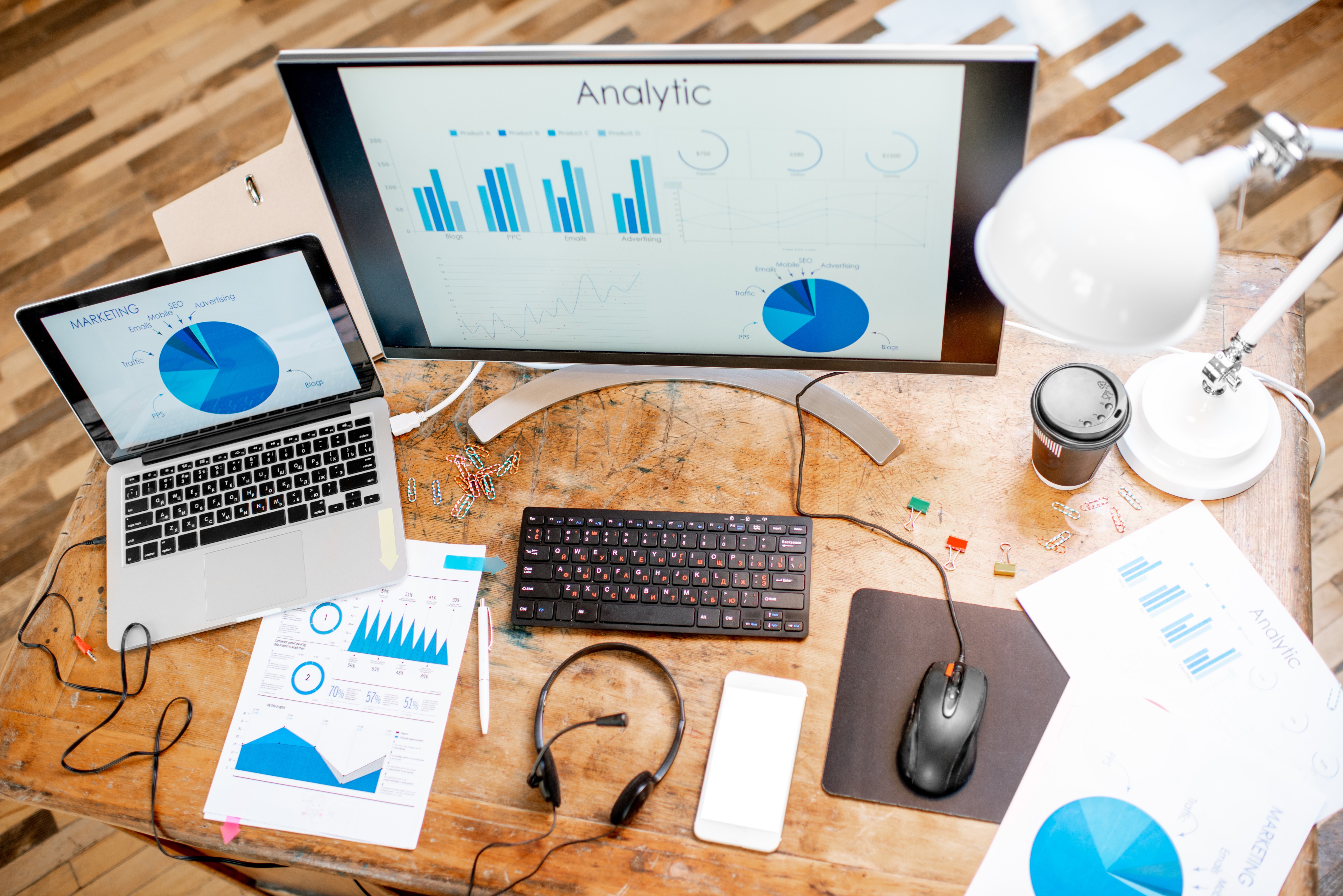 Desk with laptop and monitor showing analytic charts